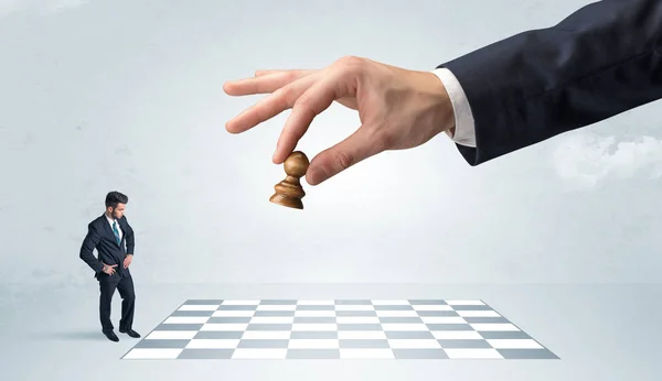 Pequeno homem de negócios jogando xadrez com um conceito de mão grande — Fotografia de Stock