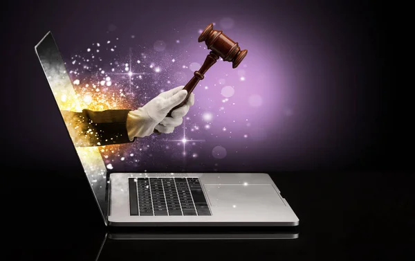 Hand with hammer coming out of a laptop