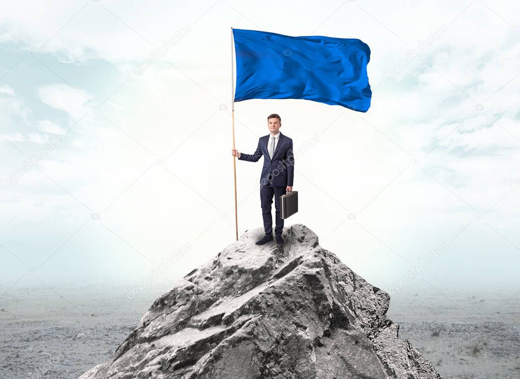 Businessman on the top of a the mountain holding flag