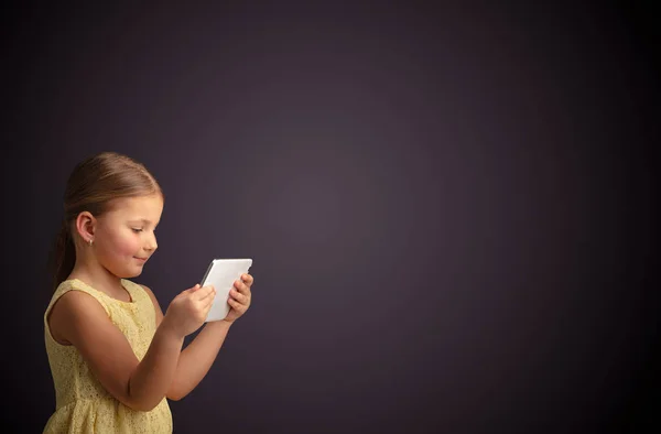 Schattig klein meisje tablet met donkere achtergrond — Stockfoto