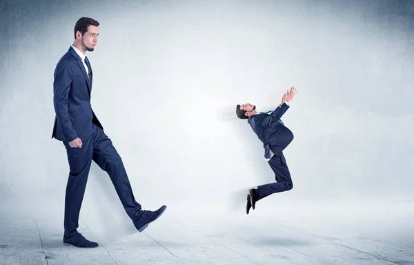 Big businessman kicking small businessman — Stock Photo, Image