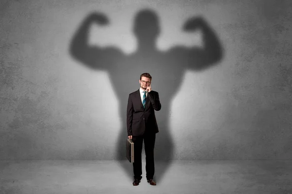 Businessman with muscular shade behind his back — Stock Photo, Image