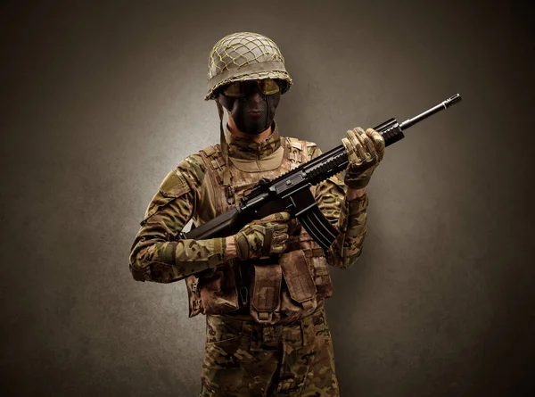 Soldat i et mørkt rom med armer. – stockfoto
