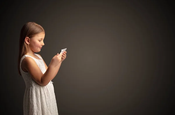 Nettes kleines Mädchen mit Tablet mit dunklem Hintergrund — Stockfoto