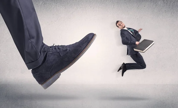 Small businessman kicked by big shoe — Stock Photo, Image