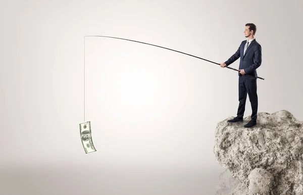 Hombre de negocios pescando dólar desde una roca — Foto de Stock