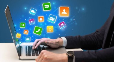 Uygulama simgeleri etrafında uçan ile dizüstü kullanarak ele