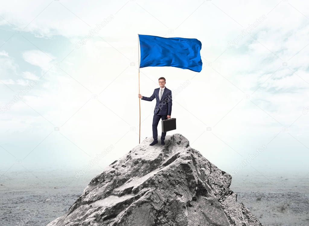 Businessman on the top of a the mountain holding flag