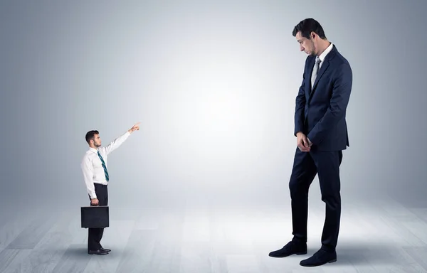 Pequeno empresário apontando para um empresário gigante — Fotografia de Stock