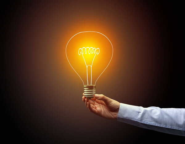 рука держа лампочку на темном фоне