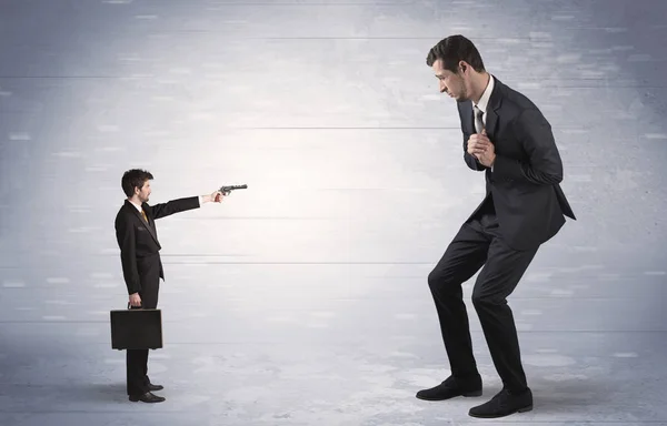 Small businessman shooting giant businessman — Stock Photo, Image