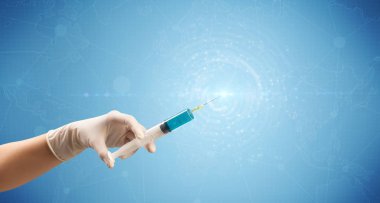 Kadın doktor elinde şırınga tutuyor.