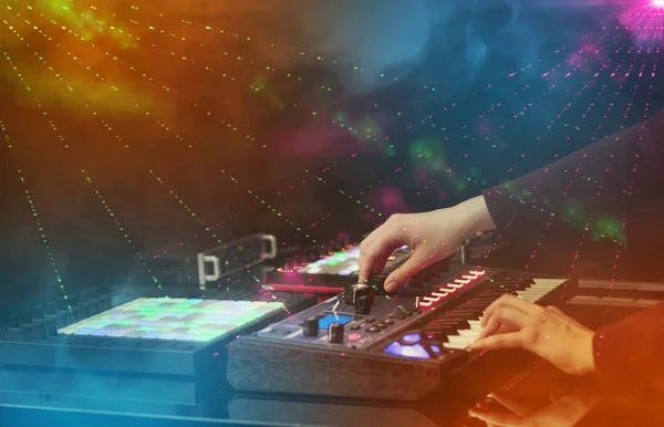 Mão misturando música no controlador dj com as cores do clube de festa ao redor — Fotografia de Stock