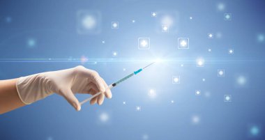 Kadın doktor elinde şırınga tutuyor.