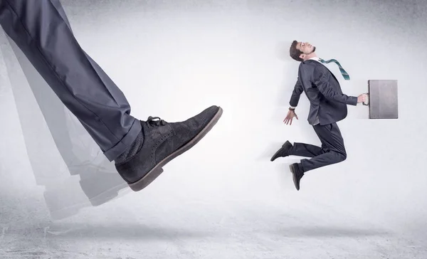 Black shoe kicking small man — Stock Photo, Image