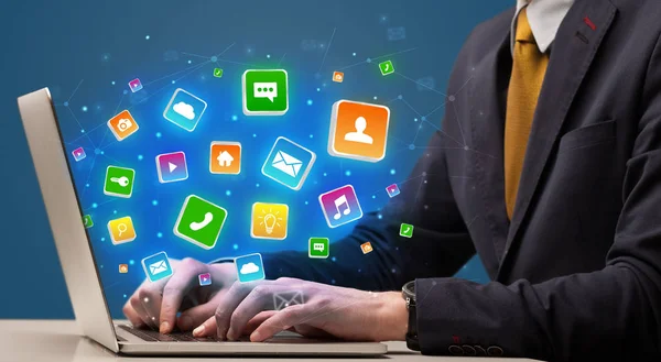 Hand using laptop with application icons flying around — Stock Photo, Image