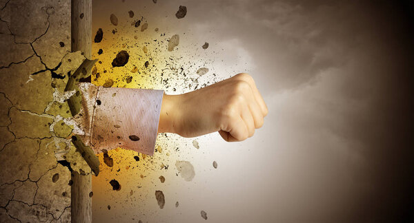 Рука сильно бьет и ломает каменную стену
