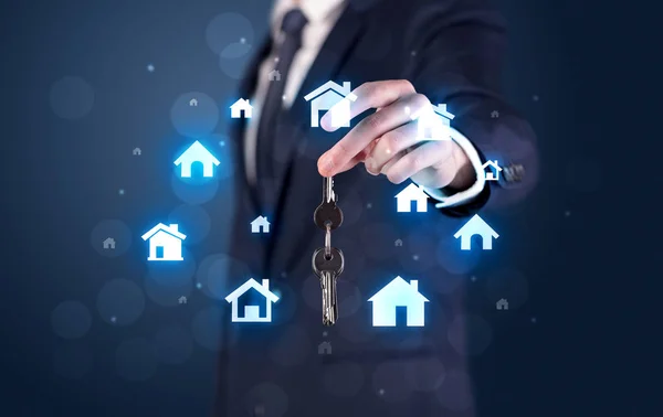 Businessman holding keys with houses around — Stock Photo, Image