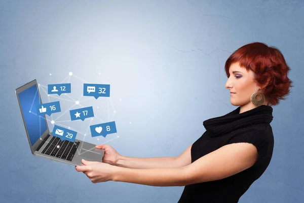 Женщина держит ноутбук с уведомлениями в социальных сетях — стоковое фото