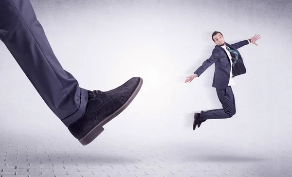 Young worker kicked out by big foot — Stock Photo, Image