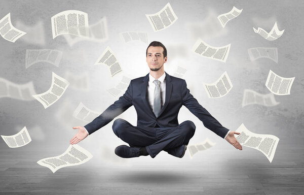 Бизнесмен медитирует с концепцией летающей бумаги
