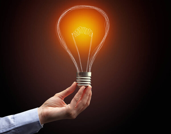 рука держа лампочку на темном фоне