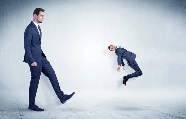 Big businessman kicking small businessman — Stock Photo, Image