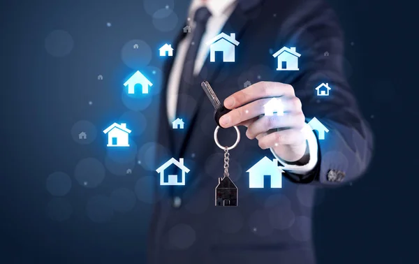 Empresario sosteniendo llaves con casas alrededor —  Fotos de Stock