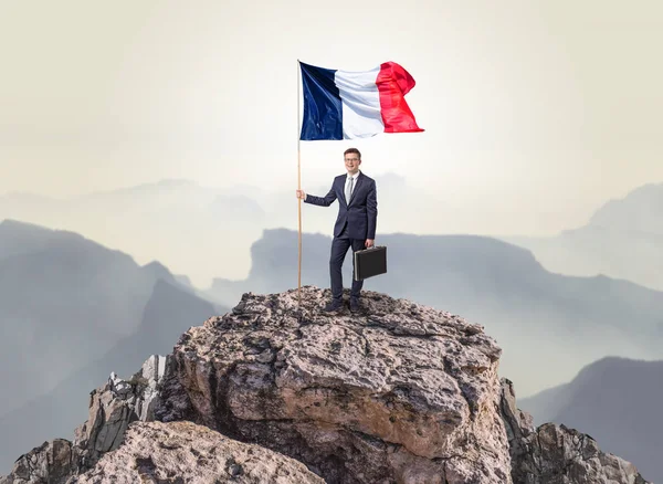 Businessman on the top of a rock holding flag — Stock Photo, Image