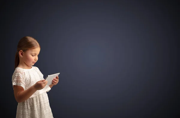 Linda niña usando tableta con fondo oscuro —  Fotos de Stock