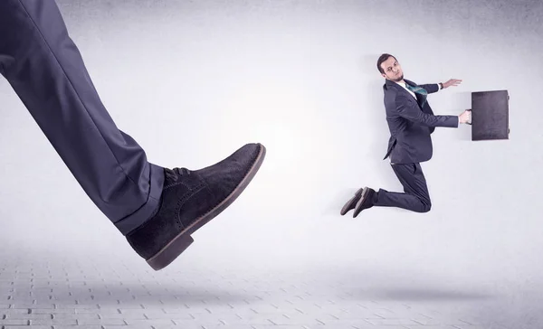 Young worker kicked out by big foot — Stock Photo, Image