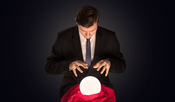 Handsome businessman with magic ball and dark empty background