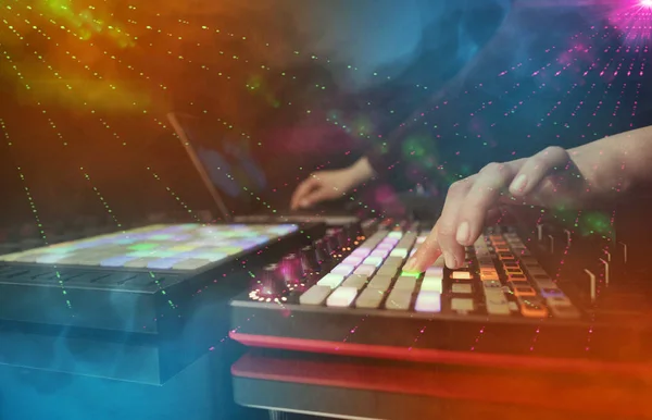 Main mélangeant la musique sur contrôleur dj avec les couleurs du club de fête autour — Photo