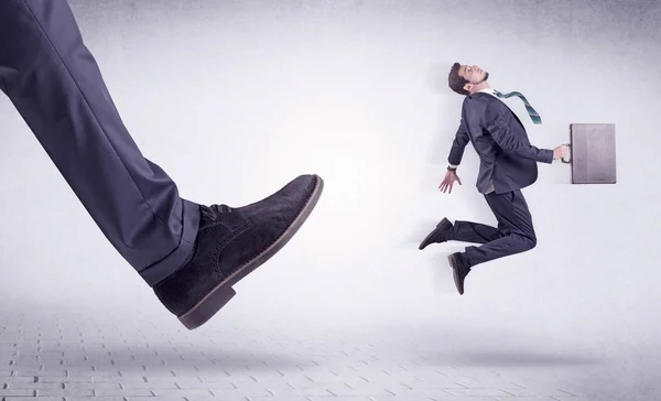 Young worker kicked out by big foot — Stock Photo, Image