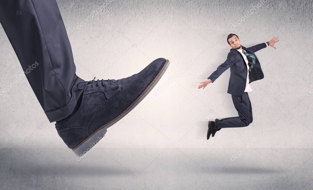 Small businessman kicked by big shoe