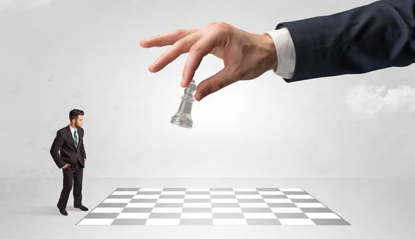 Pequeño hombre de negocios jugando al ajedrez con un gran concepto de mano — Foto de Stock