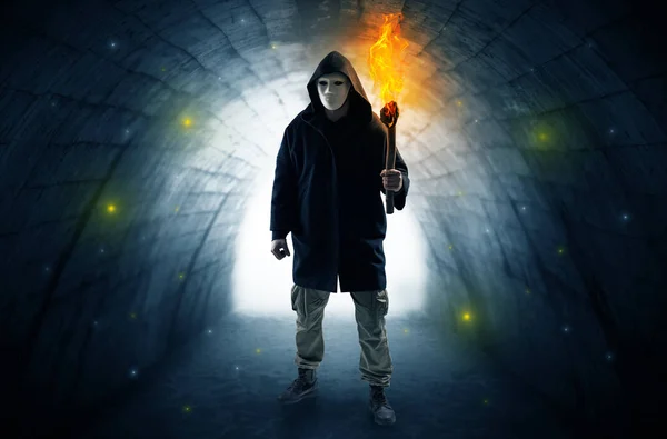 暗いトンネルにかざしたを燃焼入れて歩いている男 — ストック写真