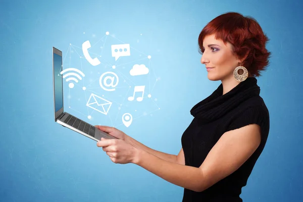 Женщина держит ноутбук с онлайн символами — стоковое фото