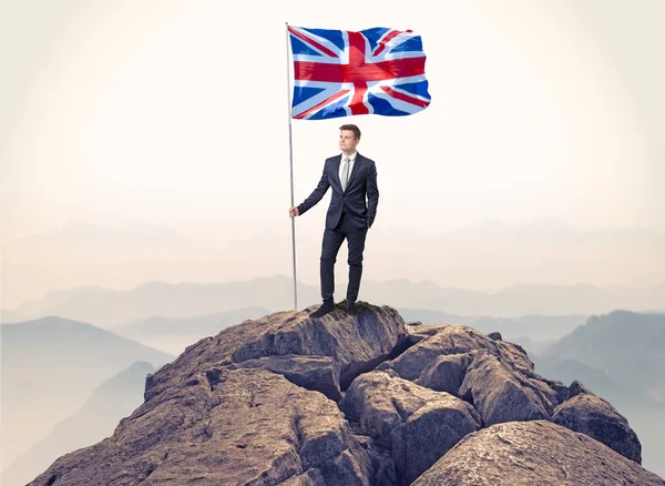 Zakenman op de top van een rots vlag houden — Stockfoto