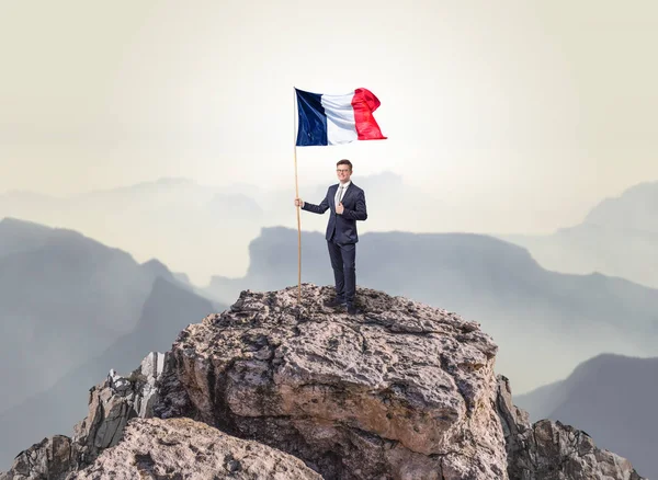 Homme d'affaires sur le dessus d'un drapeau d'attente de roche — Photo