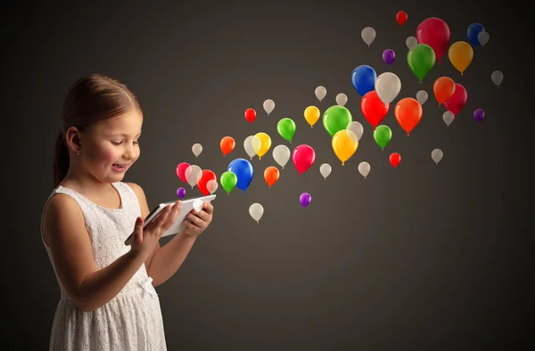 Lány gazdaság tabletta-val színes léggömb körül — Stock Fotó