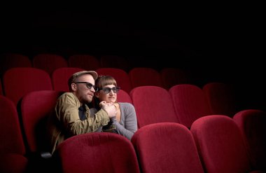 Genç çift kırmızı sinemada oturuyor