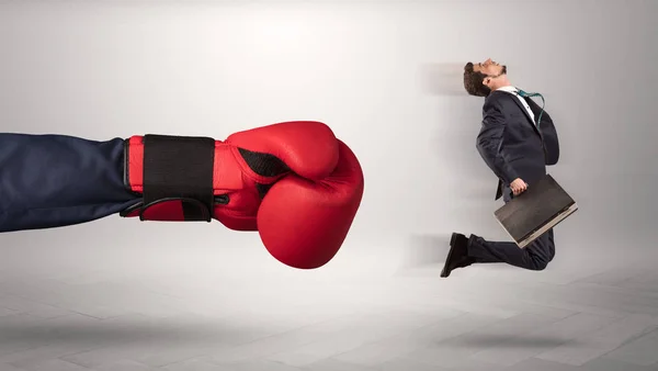 Giant hand ger en kick till en liten affärsman — Stockfoto