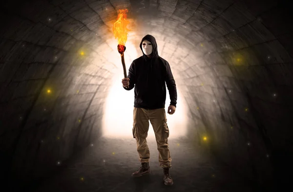 Homem caminhando com flambeau ardente em um túnel escuro — Fotografia de Stock