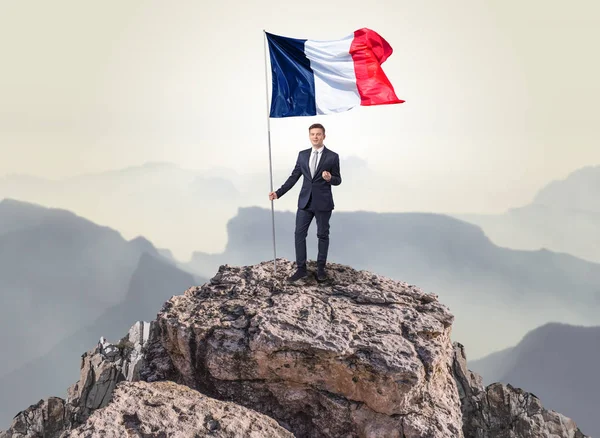 Businessman on the top of a rock holding flag — Stock Photo, Image