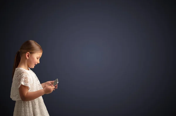 Nettes kleines Mädchen mit Tablet mit dunklem Hintergrund — Stockfoto