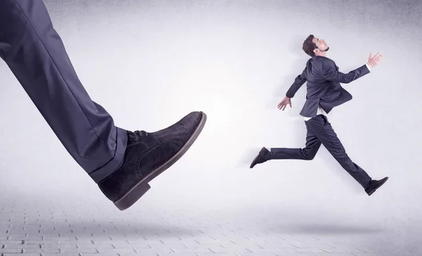 Young worker kicked out by big foot — Stock Photo, Image