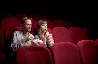Genç çift kırmızı sinemada oturuyor