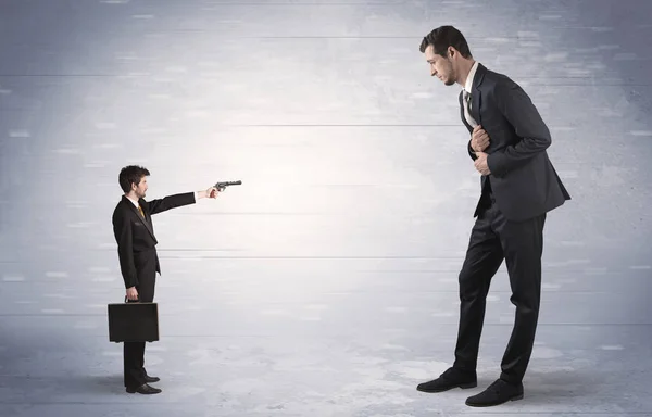 Small businessman shooting giant businessman — Stock Photo, Image