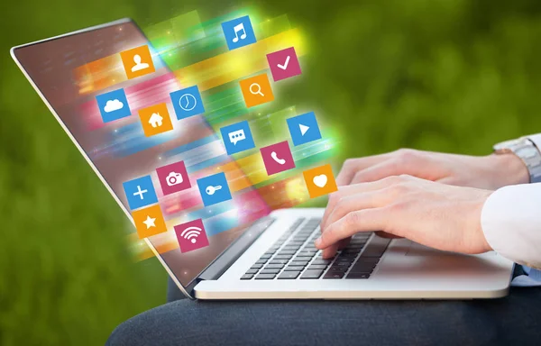 Hand using laptop with colorful application icons and symbols concept — Stock Photo, Image